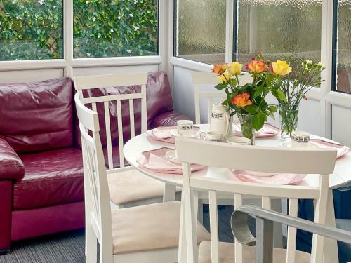 a table with a vase of flowers on it at The Bay Cottage in Thornton