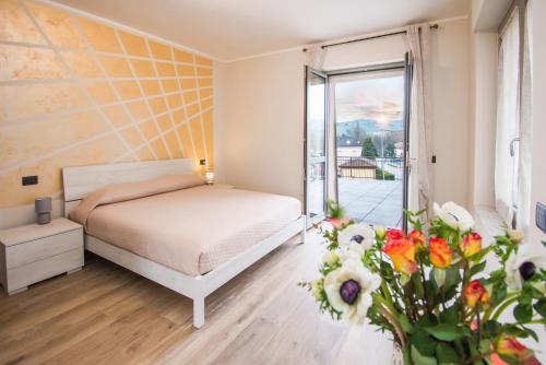 a bedroom with a bed and a window and flowers at Casa Baratta - La terrazza sulle Langhe in Neive