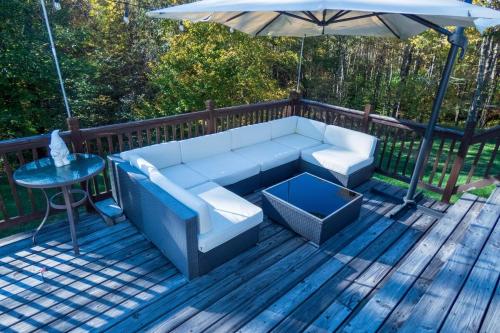 a white couch sitting on a deck with an umbrella at Chic Catskills Farmhouse in Harris