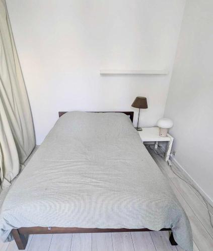 Ce lit se trouve dans un dortoir blanc doté d'une table et d'une lampe. dans l'établissement Moderne appart central 2 personnes, à Paris
