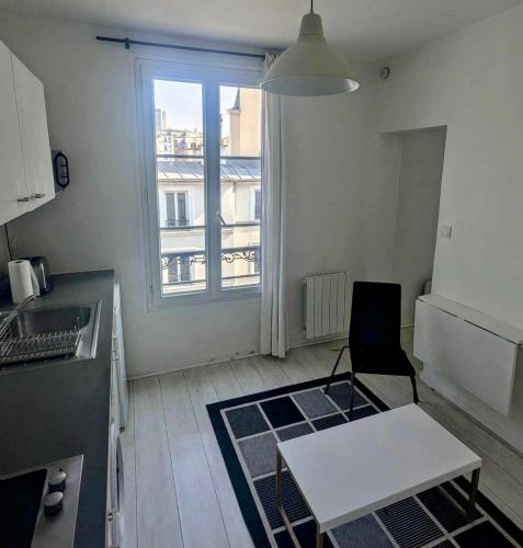 une petite cuisine avec une table et une fenêtre dans l'établissement Moderne appart central 2 personnes, à Paris
