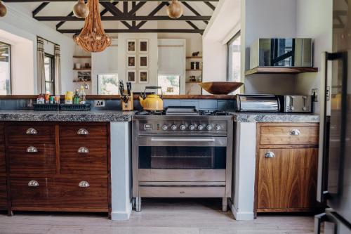 a kitchen with a stainless steel stove and wooden cabinets at Rockwood Karkloof Forest Lodge & Mountain Cabin in Karkloof Nature Reserve