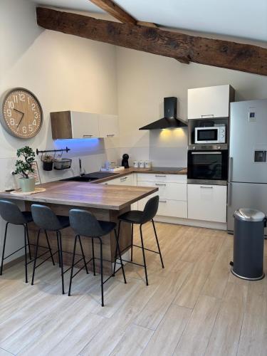 une cuisine avec une table en bois et une horloge au mur dans l'établissement Le ST PIERRE, joli T2 entièrement rénové en plein coeur du centre ville, à Mâcon