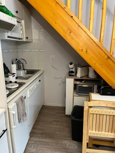 une cuisine avec des appareils blancs et un escalier en bois dans l'établissement Charmant duplex en plein centre de Cauterets de 4 à 6 couchages et 2 chambres dont une sous-toit, à Cauterets