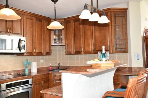 a kitchen with wooden cabinets and a counter top at Oceanfront Paradise: Penthouse with Peloton in Lowlands