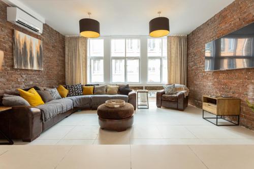 a living room with a couch and a brick wall at Luxury Penthouse with Private Roof Terrace in Manchester