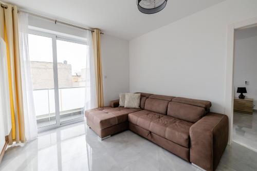 a brown couch in a living room with a large window at Stunning 2BR Apartment in Sliema - APT 23 in Sliema