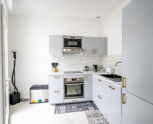 a kitchen with white cabinets and a microwave at Bordeaux cosy home in Bordeaux