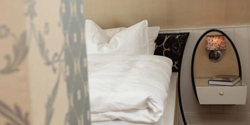 a bed with white sheets and pillows next to a mirror at Landhaus Spatzenhof in Wermelskirchen