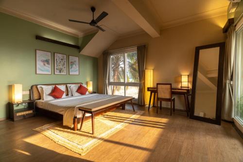 a bedroom with a bed and a table and a window at Kssemya in Mandrem