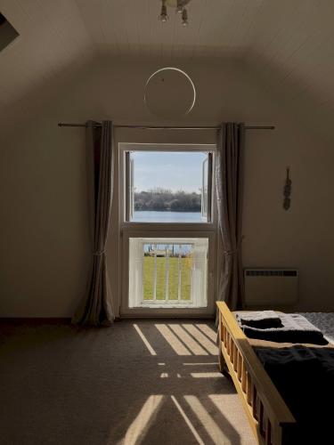 a bedroom with a bed and a large window at Medway Hot Tub Lodge in South Cerney