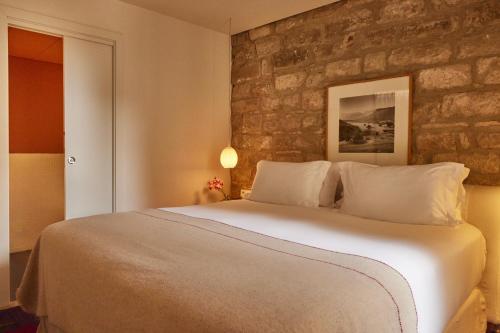 a bedroom with a large bed with a stone wall at Hotel Neri – Relais & Chateaux in Barcelona