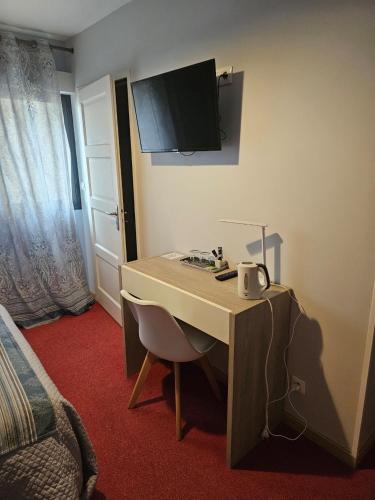 a room with a desk with a tv on the wall at Les chambres du grès in Ambres