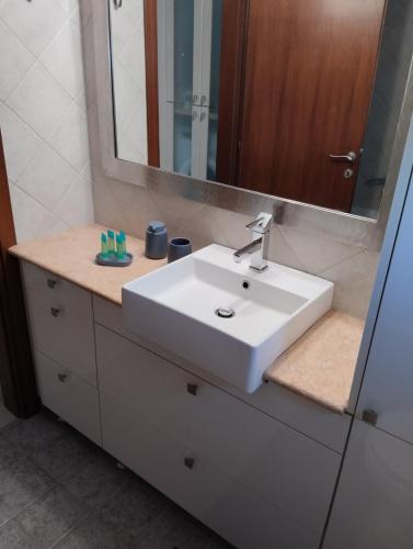 a bathroom with a white sink and a mirror at summer time in Neoi Epivates