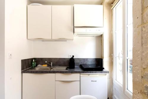 une cuisine avec des armoires blanches et un évier dans l'établissement Charmant studio en plein coeur du centre-ville, à Caen