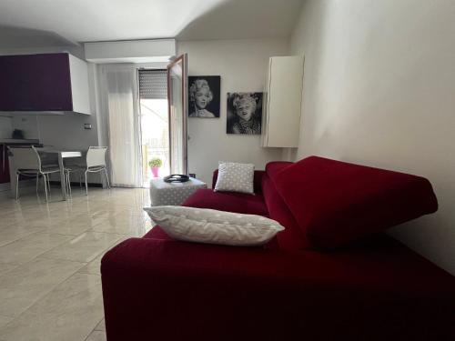 a living room with a red couch and a kitchen at Sky House in Piacenza