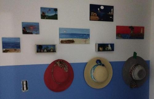 a group of hats hanging on a wall with pictures at Apto frente pro mar 3 pedra in Itapoa