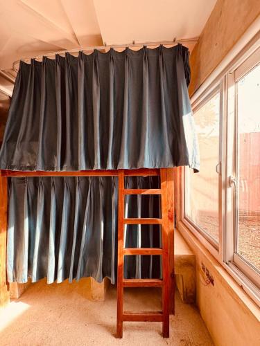 a bunk bed with a ladder next to a window at Compass Hostel in Nungwi