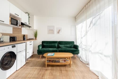 un salon avec un canapé vert et une table dans l'établissement Le Noyer - appartement moderne & accessible, à Montaigu-Vendée