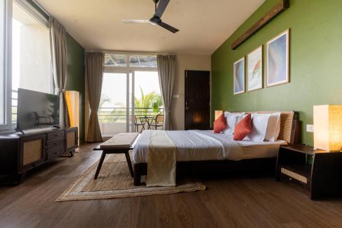 a bedroom with a large bed with green walls at Kssemya in Mandrem