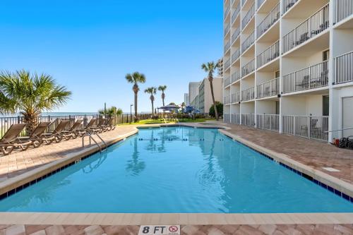 a swimming pool in front of a building with chairs at Indigo in Myrtle Beach
