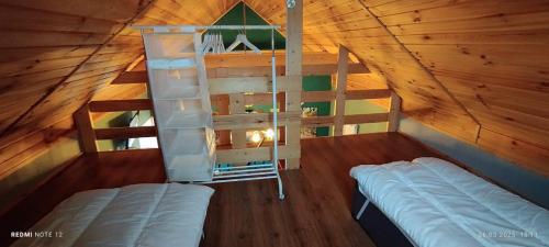 an attic room with two beds and a ladder at Żurawisko - Domki wśród natury in Jesiona