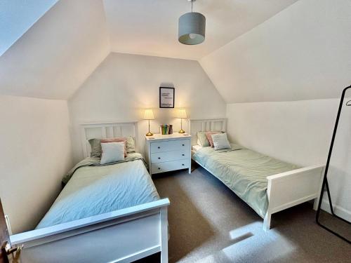 two twin beds in a attic bedroom with a dresser at The Cottage in Aberdeen