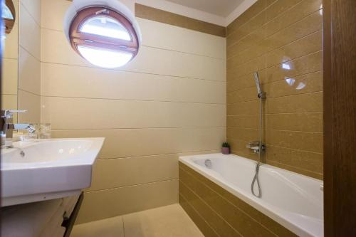 a bathroom with a sink and a tub and a window at Duna Garden Hotel in Budapest
