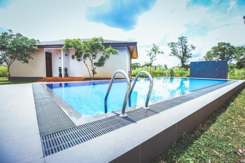 a swimming pool in front of a house at Ceyloni Sigiriya in Dambulla