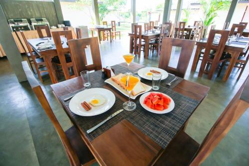 a table with plates of eggs and fruit on it at Ceyloni Sigiriya in Dambulla