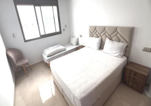 a bedroom with a large white bed and a chair at PUERTO MARINA ASILAH in Asilah