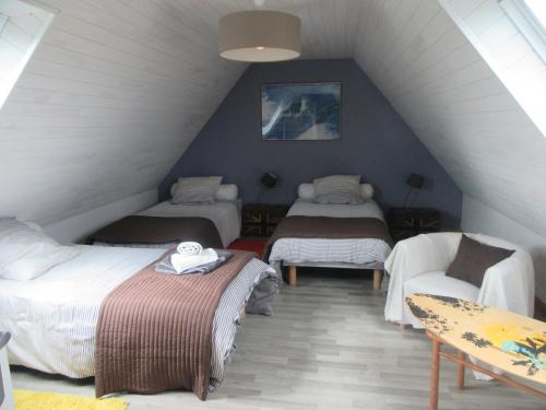 Cette chambre mansardée comprend deux lits et un canapé. dans l'établissement Maison de vacances avec jardin clos à 300m de la mer, à Pouldreuzic