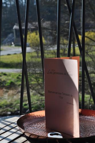 a book sitting on a plate on a table at Les Terrasses de l'Our in Paliseul