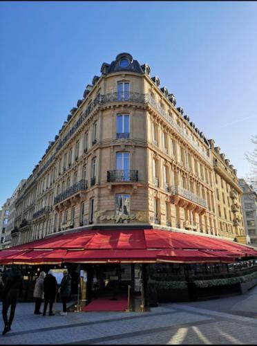 un grand bâtiment avec un auvent rouge en face dans l'établissement Luxury Loft Champs Élysée, à Paris