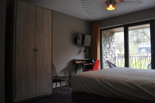 a bedroom with a bed and a sliding glass door at Les Terrasses de l'Our in Paliseul