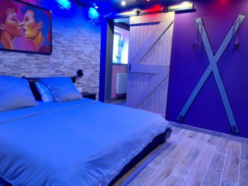 une chambre avec un grand lit et un mur violet dans l'établissement L'art du désir, à Le Saulcy