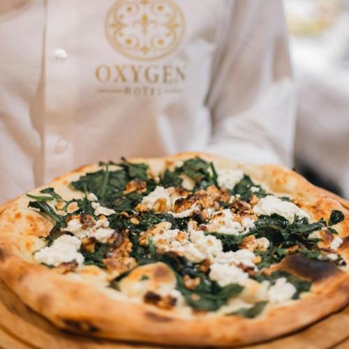 a pizza sitting on top of a wooden cutting board at Oxygen Boutique Hotel in Tirana