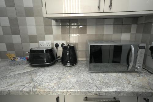 a kitchen counter with a microwave and appliances on it at Charming Oxford Apartment in Telford - Flat 1 in Telford