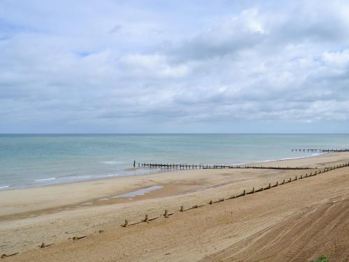 a sandy beach with a pier in the ocean at Roses Place in Bacton