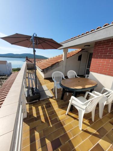 a patio with a table and chairs and an umbrella at Villa Kaktusa in Pirovac