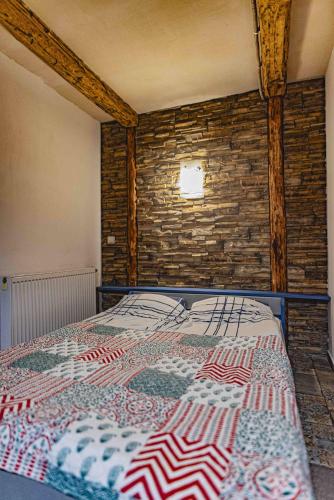 a bed in a room with a brick wall at Folwark Malinowy Chruśniak in Bisztynek