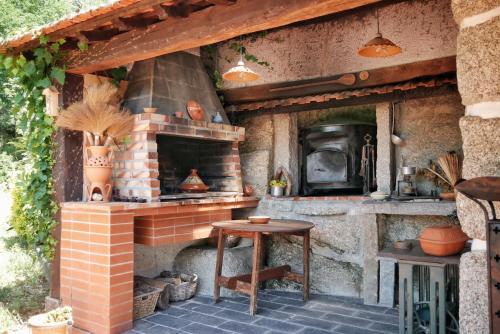 an outdoor kitchen with a brick oven and a table at Quinta de Fornelo - Família Campos in Amarante