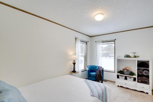 a white bedroom with a bed and a blue chair at Stylish Chetek Hideaway with Lake and Dock Access! in Chetek