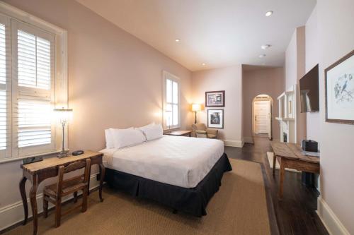 una camera da letto con un letto, un tavolo e una scrivania di Melrose Mansion a New Orleans