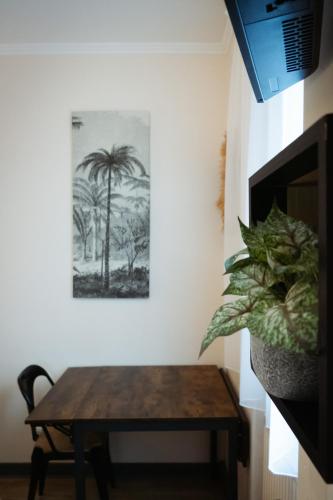 une table et une plante dans une pièce avec une photo sur le mur dans l'établissement Hôtel de la gare, à Choisy-le-Roi