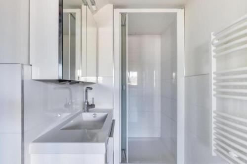une salle de bain blanche avec un lavabo et une douche dans l'établissement Appartement d'Artiste, Terrasse Vue Tour Eiffel, à Paris