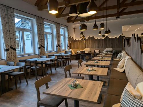 a restaurant with wooden tables and chairs and windows at BSW Hotel Isarwinkel in Bad Tölz