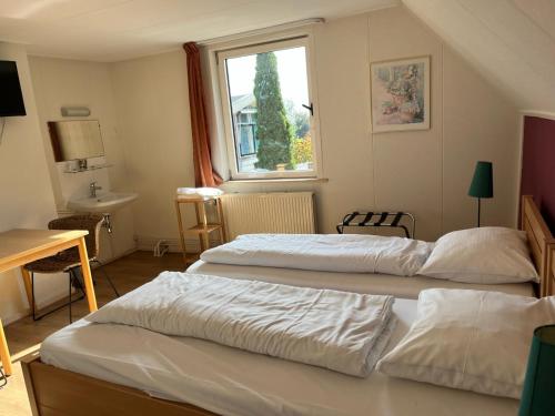 a hotel room with two beds and a window at Hotel De Oude Molen in Groesbeek