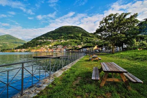 a picnic table next to a lake with mountains in the background at Domaso front lake in Domaso