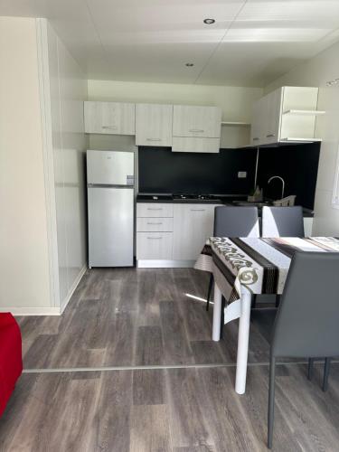 a kitchen with white cabinets and a table and a refrigerator at Campeggio Punta di Crabbia in Pettenasco